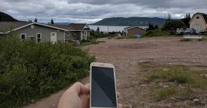 picture shows person's hand, holding a smartphone in remote region
