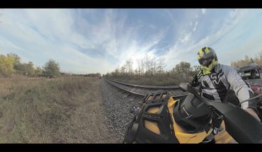 ATV drives alongside railroad tracks in summer scene
