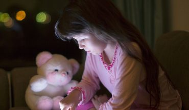 young child's face illuminated by smartphone screen