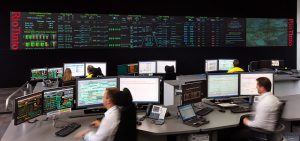 high tech computer centre with giant screens, human operators watching