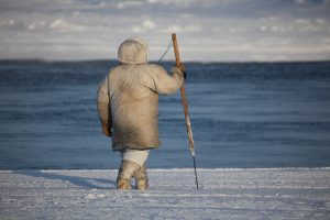 man with harpoon walking on open ice