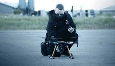 man wewaring mask checks small drone on tarmac