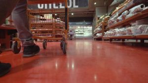 man pushes grocery cart down aisle