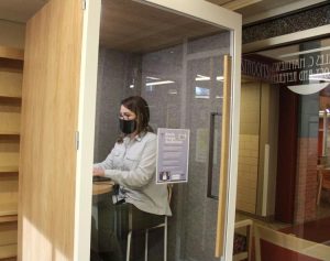 woman wearing face mask sits in privacy booth