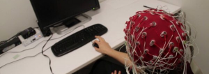 patient sitting a computer wears cap with sensors