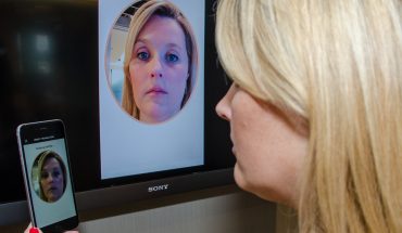 woman looks at face on smartphone, ATM screen