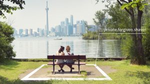 couple sit on park bench looking at Toronto skyline; they are surrouned by superimposed white square