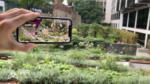 hand holds smartphone in outdoor garden; garden image and graphic overlay is reproduced on smartphone screen