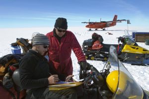 men on snowmobiles prepare for Antarctic trip