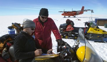 men on snowmobiles prepare for Antarctic trip