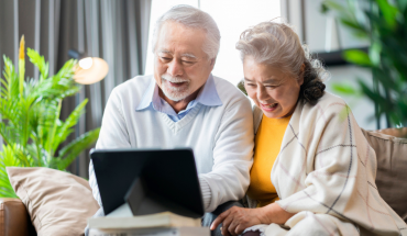 Older man and woman enjoy session on laptop computer.