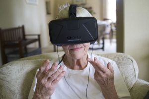 older woman wearing VR goggles, hands held up in action gesture