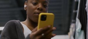 young woman listening to earbuds looks at smartphone screen