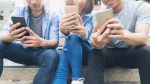 young people sit together as they look at their smartphones