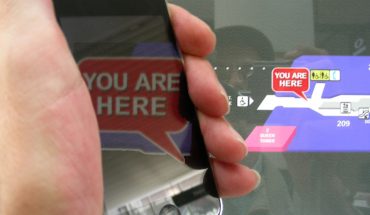 hand holds smartphone, screen show words You Are Here