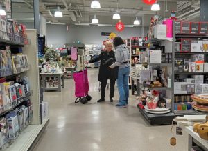 female shopper with cart speaking with store staff member in retail setting