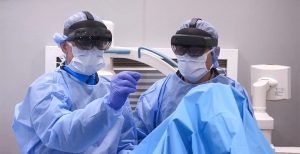 two surgeons wearing masks, gowns and mixed reality headsets.