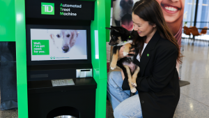 woman holding small dog kneels by 'ATM'