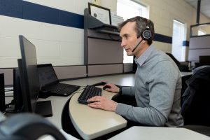 man seated at computer desk wears headphones