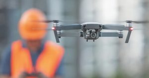 drone in flight in front of man in construction hardhat