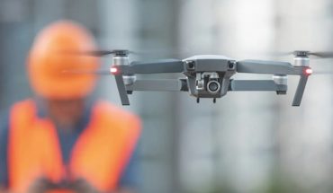 drone in flight in front of man in construction hardhat