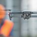 drone in flight in front of man in construction hardhat