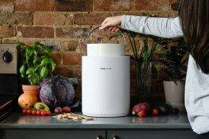 FoodCycler on counter top; arm reaching over to grab handle on top.