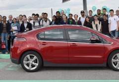 college students standing around a parked electric vehicle