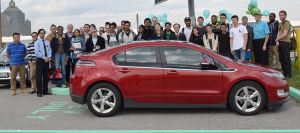 college students standing around a parked electric vehicle