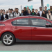 college students standing around a parked electric vehicle