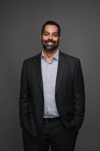 man in open jacket smiles at camera