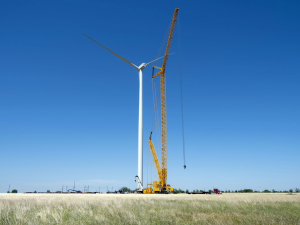 tall crane lifts windmill tower in open countryside