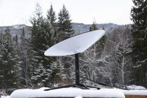 a satellite dish sits on a snowy rooftop