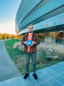 man holds award plaque outside Apple HQ