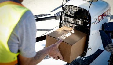 man places cardboard box into drone for delivery