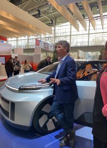 man stands next to car speaking to crowd