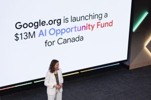 woman stands on stage in front of Google sign