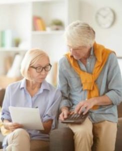 two older women review paper documents and calculator