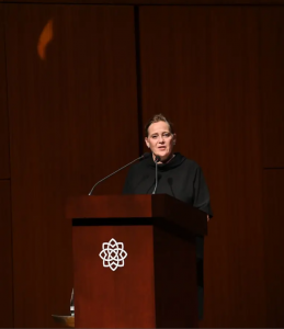 woman speaks at podium in darkened hall