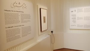 museum display about calligraphy shows art on wall, audio listening station visible