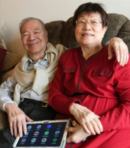 seated man and woman embrace, hold smart tablet on lap
