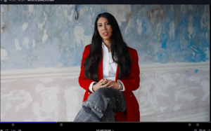 seated woman speaks to camera